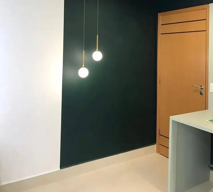 Parede em verde profundo com pendentes de vidro e porta de madeira
